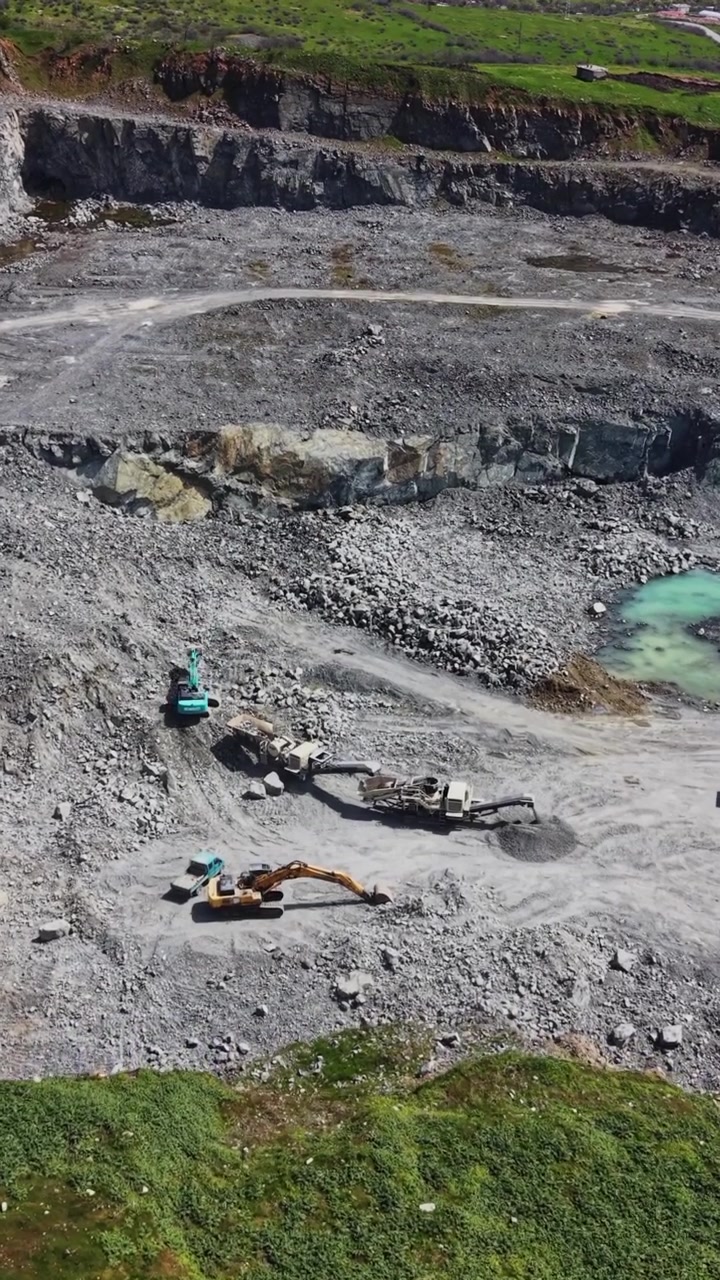 Heavy machinery working on dusty quarry floor aerial