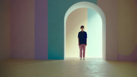 person standing in a pastel-colored room with an archway
