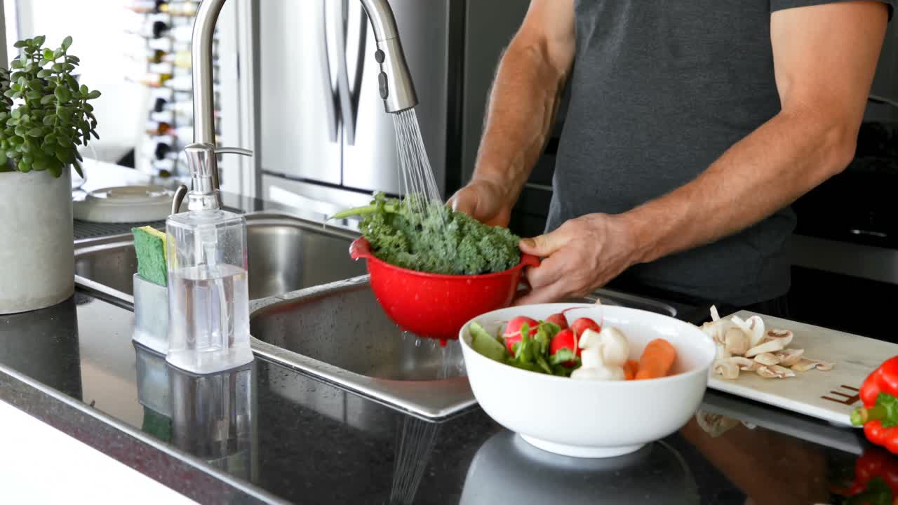 hombre lavando verduras bajo el grifo de agua en la cocina 4k