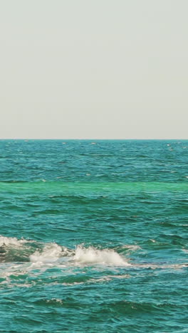 a white sailboat is floating in the sea near the coast on the background of an old pier in the summer. Seascape. Slow motion. Vertical video