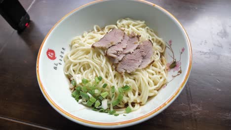 close up of typical chengdu food mi xian noodle with braised pork slices and spring onion, china