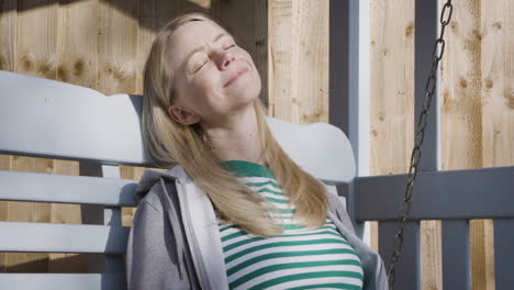 woman relaxing on a porch swing with coffee