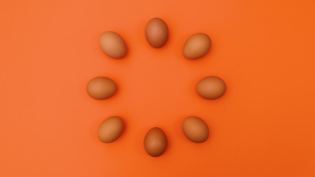 Creative moving dance of fresh eggs in circle on orange theme. Stop motion