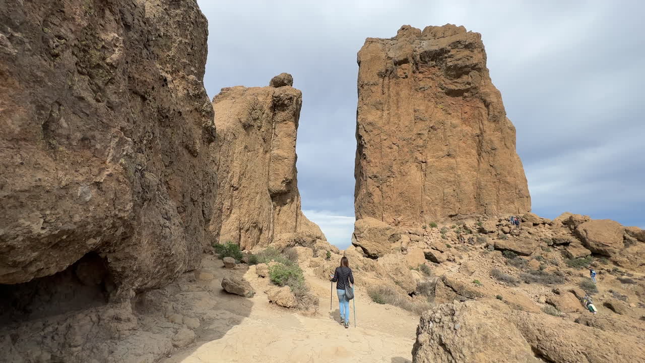Tourist walking on a path towards Roque Nublo, volcanic rock formation in Gran Canaria, Canary Islands, Spain