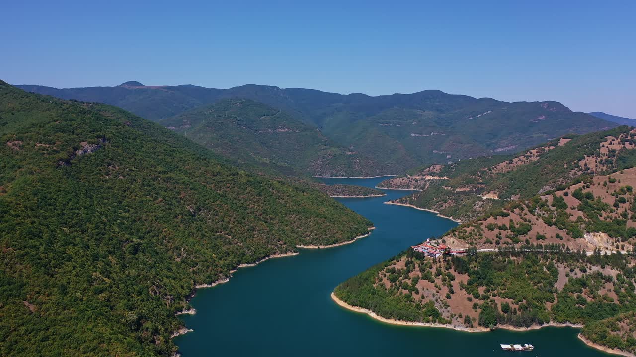 Rodop Dağları'nda tepeler arasında uçarken, görüş alanında mavi su ile havadan görünüm.