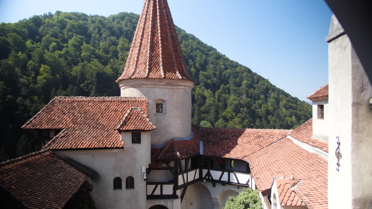 Clip showcasing the beauty of the Dracula Castle in Transylvania Romania with a dense tree filled mountain in the background