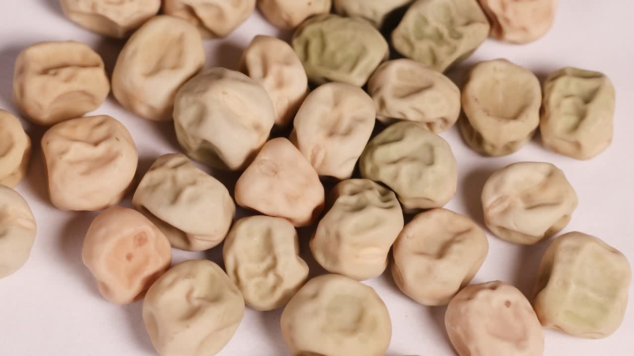 Dried beans and seeds gently move and shift on a flat surface under soft lighting