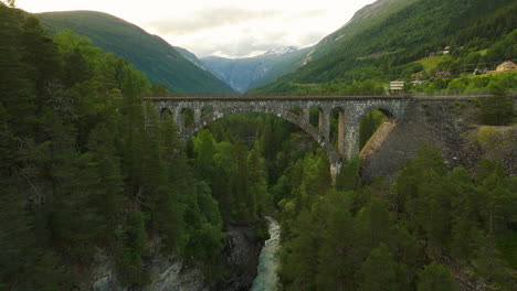 rauma river flows under kylling bru stone railway bridge, verma, norway