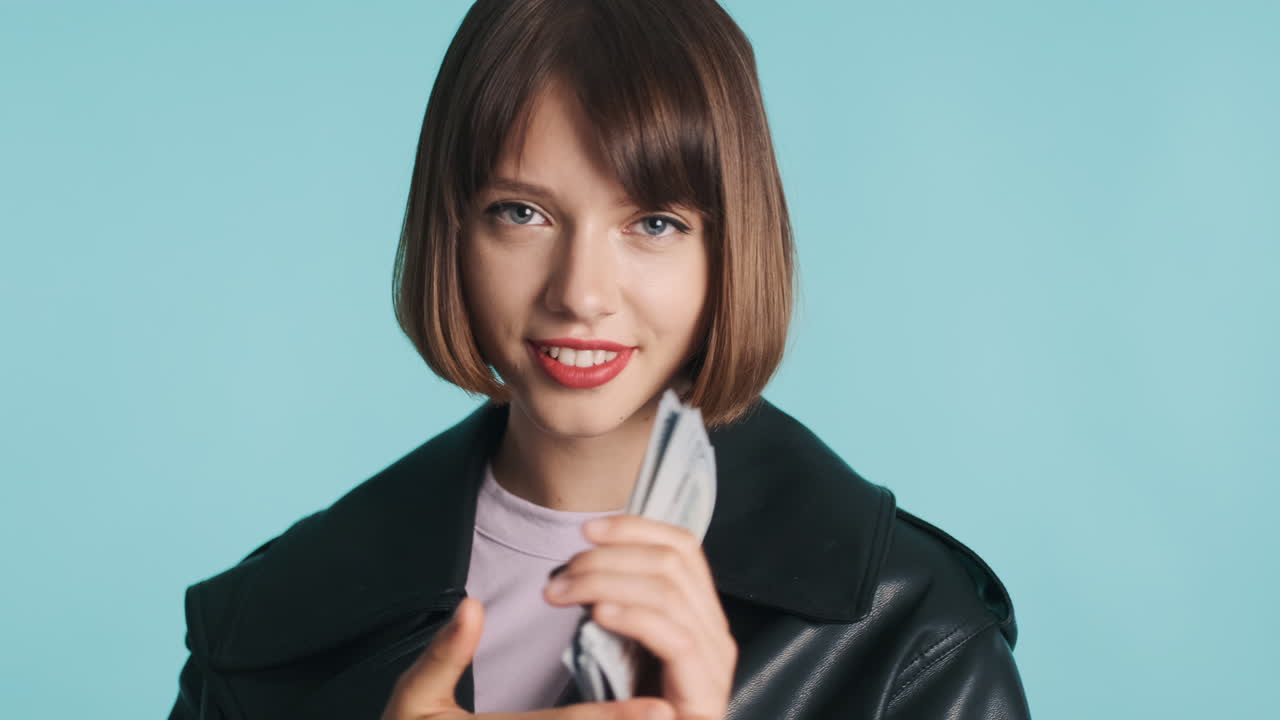 젊은 여성이 지폐를 들고 자신을 고 있습니다.