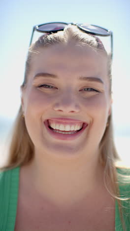 vertical video: smiling woman enjoying sunny day at beach, wearing sunglasses on head