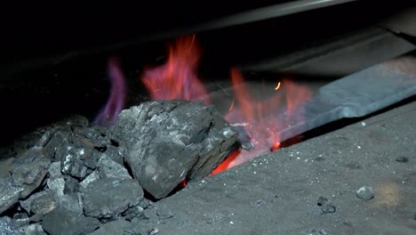 blacksmith in a fire heats metal to forge a product