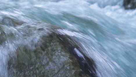 close up of river water drops over a low rock in a fast flowing river of clean fresh water