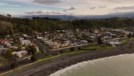 kaikoura area in new zealand during sunset time. luxury houses with ocean view. hills in background. aerial view. waves reaching pebbly beach