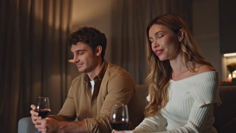 couple spending first date in cozy evening apartment holding wineglasses closeup