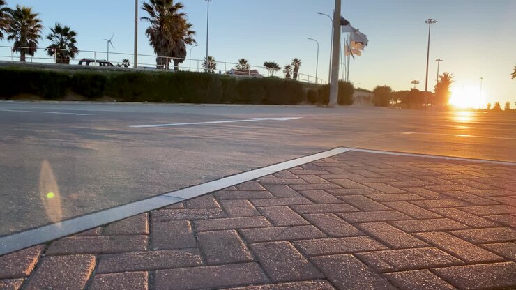 Posti auto vuoti nel parcheggio della spiaggia ricoperti di asfalto con un'enorme alba sullo sfondo