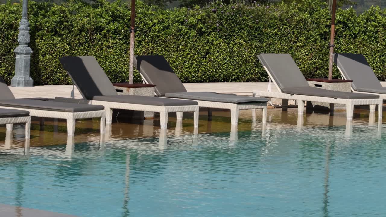 A tranquil view of poolside loungers and clear water reflecting sunlight.
