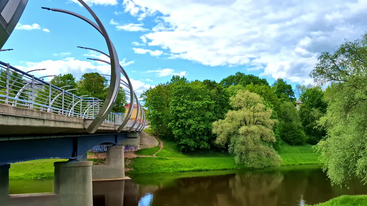 Modern bridge over Gauja river with curved metal arches in Valmiera
