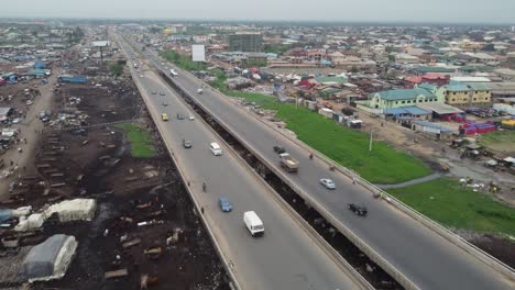 cars moving speedily on bridge of a sub-urban highway with a nigerian flag in front of an industry