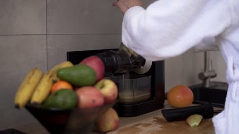 mujer exprimiendo jugo de manzana o pera por la mañana usando un exprimidor en la cocina