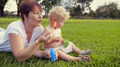 mother and baby blowing soap bubble outdoors