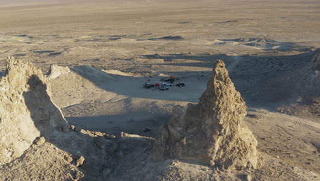 aerial shot of 2 large pinnacles overlooking a camping site with vehicles in the california desert