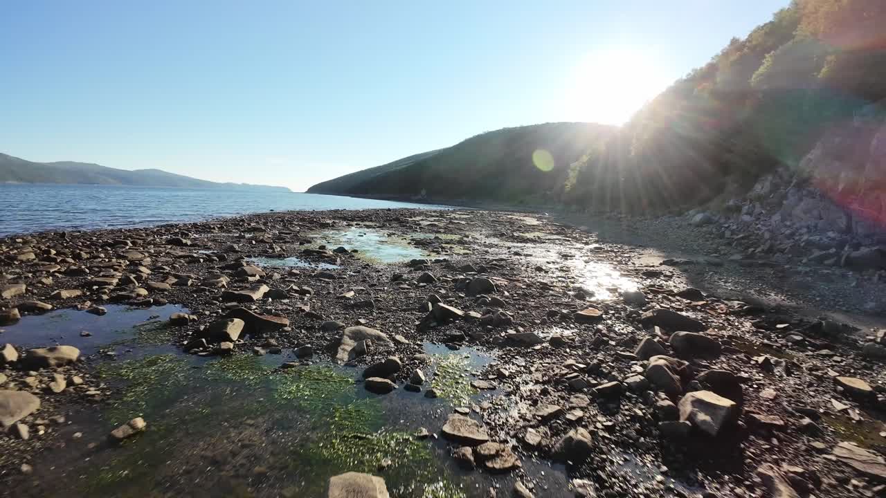 Experience breathtaking views of a rocky shoreline as the sun sets over tranquil waters