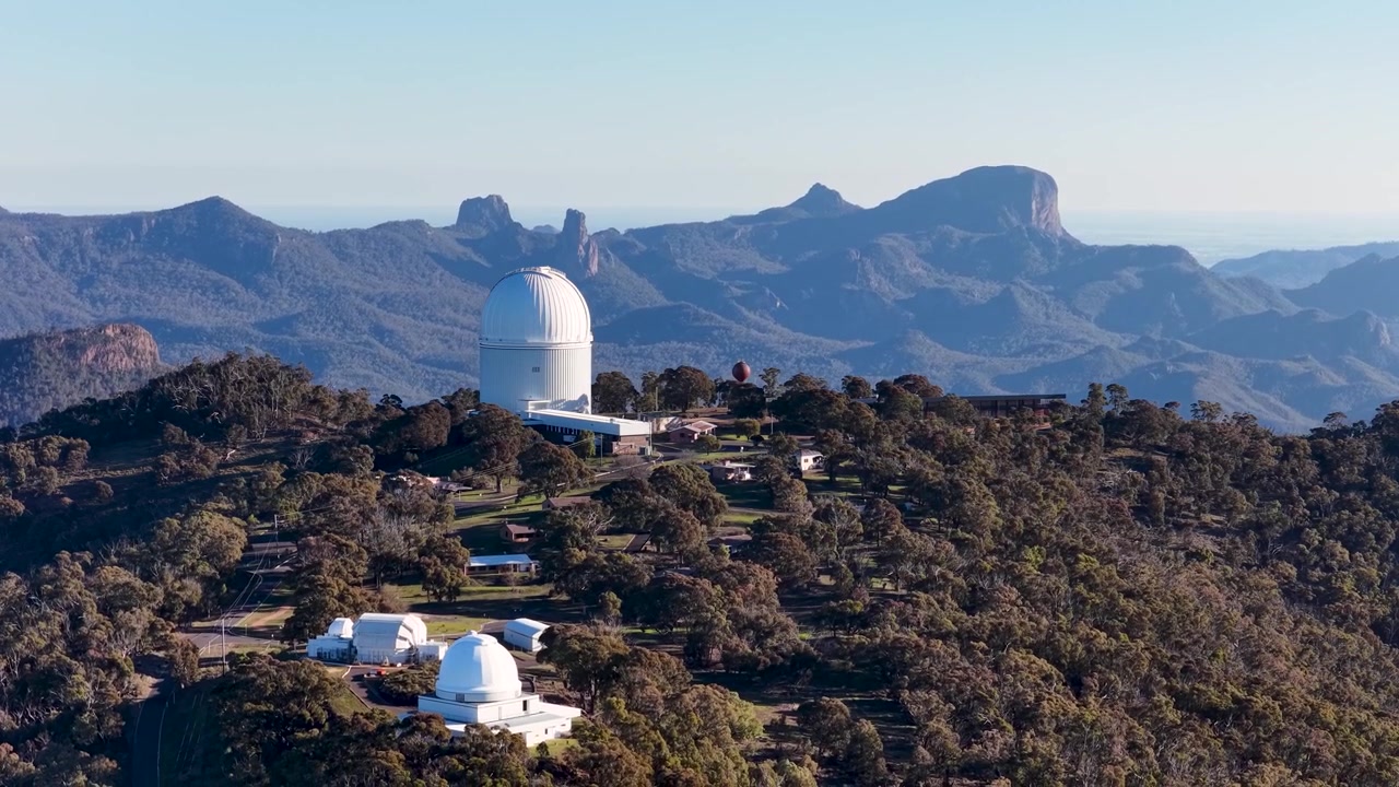 Vista aérea ampla de cúpulas de telescópios no Observatório Siding Spring, no Parque Nacional Warrumbungle.