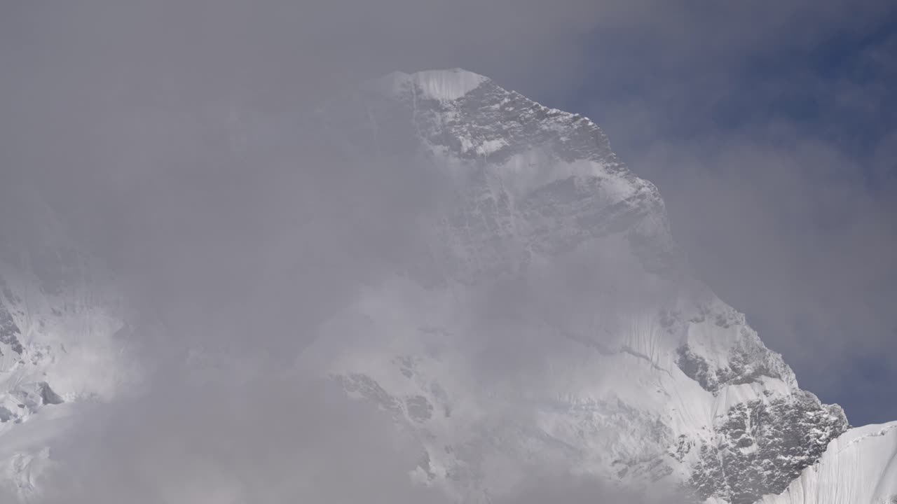 Timelapse of clouds passing a huge snowy mountain, clear blue sky, beautiful day