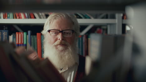 portrait of elderly professor standing among bookshelves in library