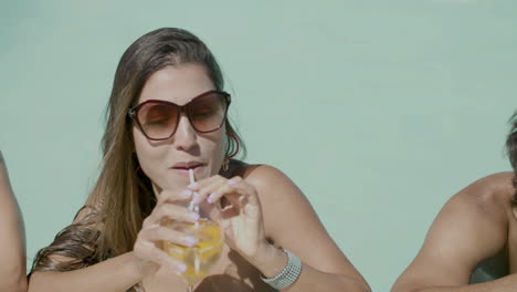 slider shot of cute people standing in swimming pool and talking with beverages