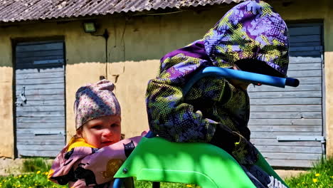 children in colorful clothes playing on a green plastic slide on sunny spring day