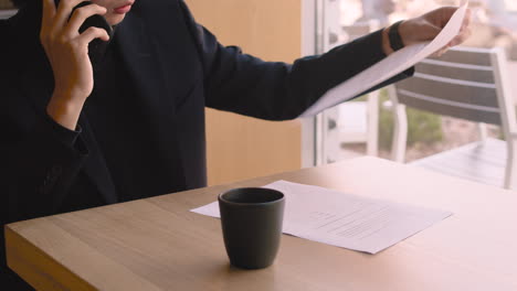 Hombre-De-Negocios-Serio-Charlando-Por-Celular-Y-Bebiendo-En-Una-Cafetería