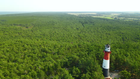 Vista-Aérea-Del-Faro-De-Stilo-Rodeado-De-Un-Exuberante-Follaje-Verde-En-Osetnik,-Polonia,-En-La-Costa-Polaca-Del-Mar-Báltico---Disparo-De-Drones