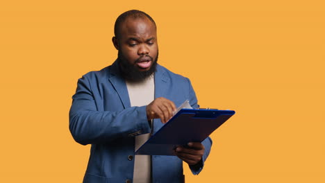 man browsing though financial audit report on clipboard, pleased by high income