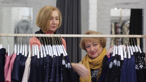 two elderly women are choosing clothes in the mall of the store. weekend shopping