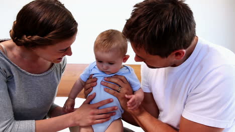 padres felices jugando con su bebé en la cama