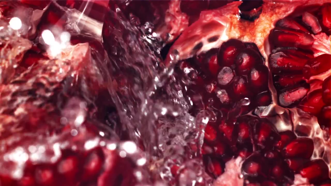 Slowmotion vand sprøjter på friske granatæblekerner