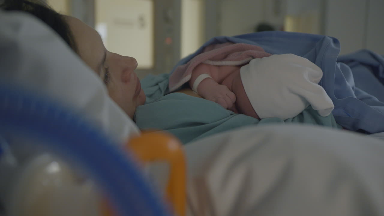Close up of newborn with mother in hospital bed, skin contact