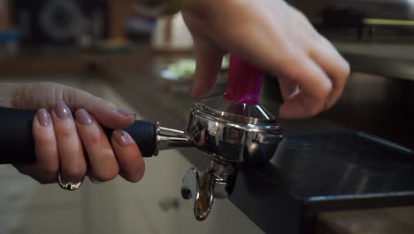 SLOWMO---Professional-female-barista-pressing-temper-on-ground-coffee