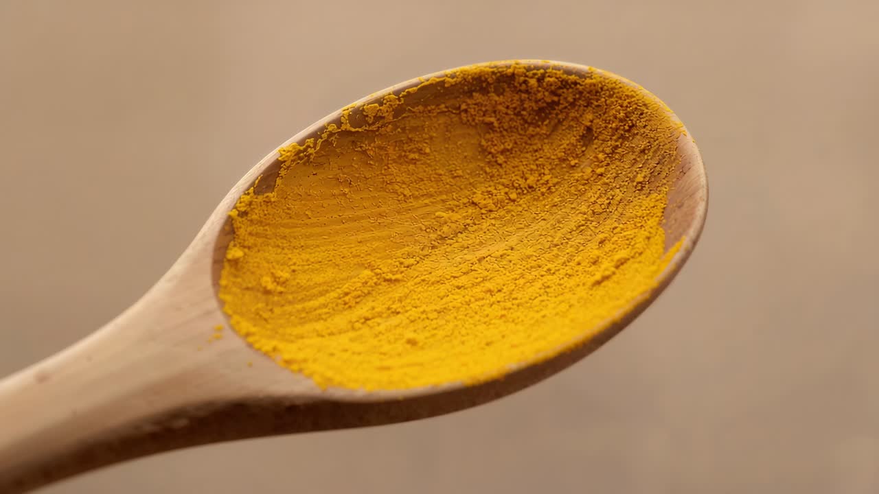 Tightening camera showing wooden spoon revealing yellow powder texture against beige backdrop