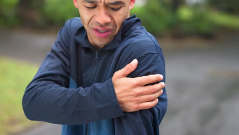 man experiencing shoulder pain outdoors