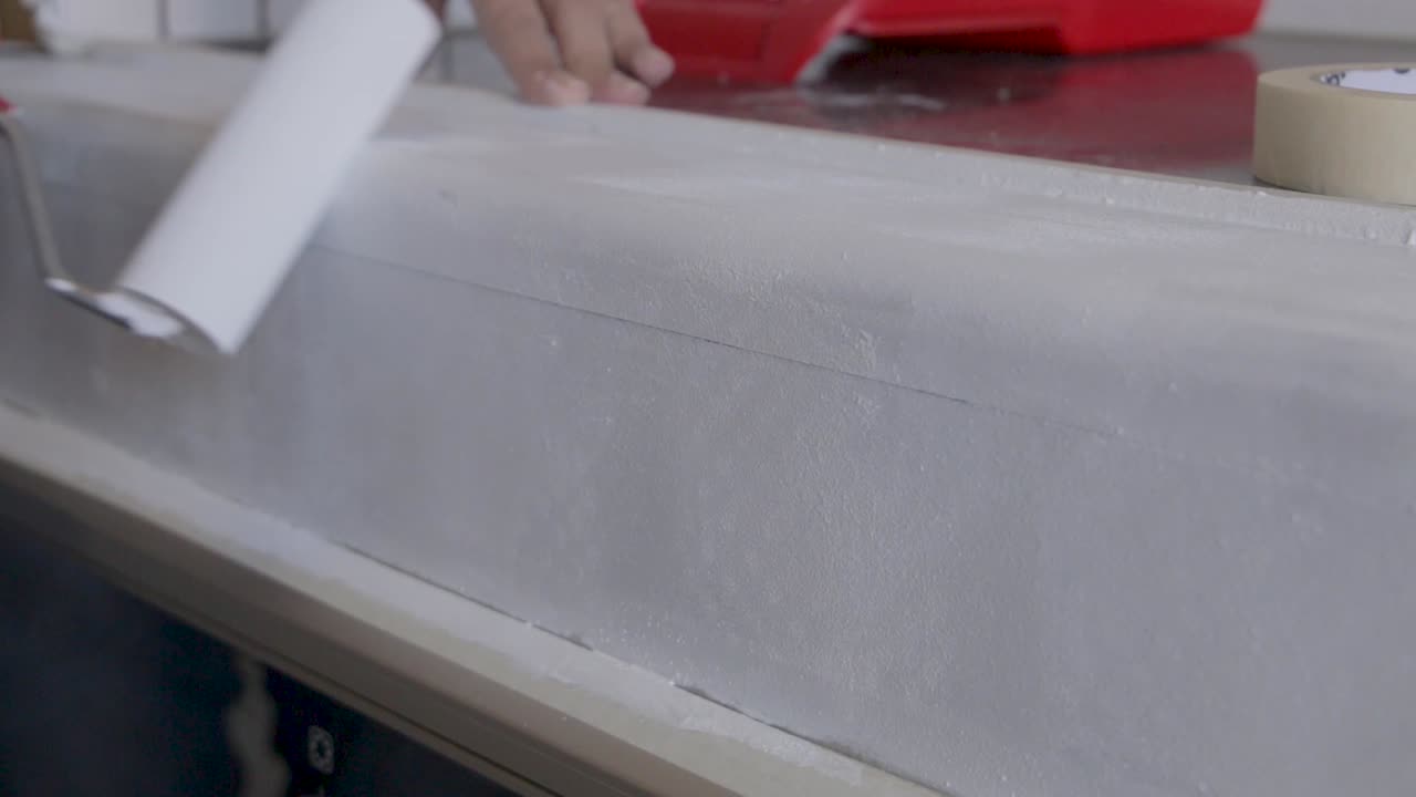 cerrado cerca de una mujer pintando imprimación en un armario con un rodillo de pintura