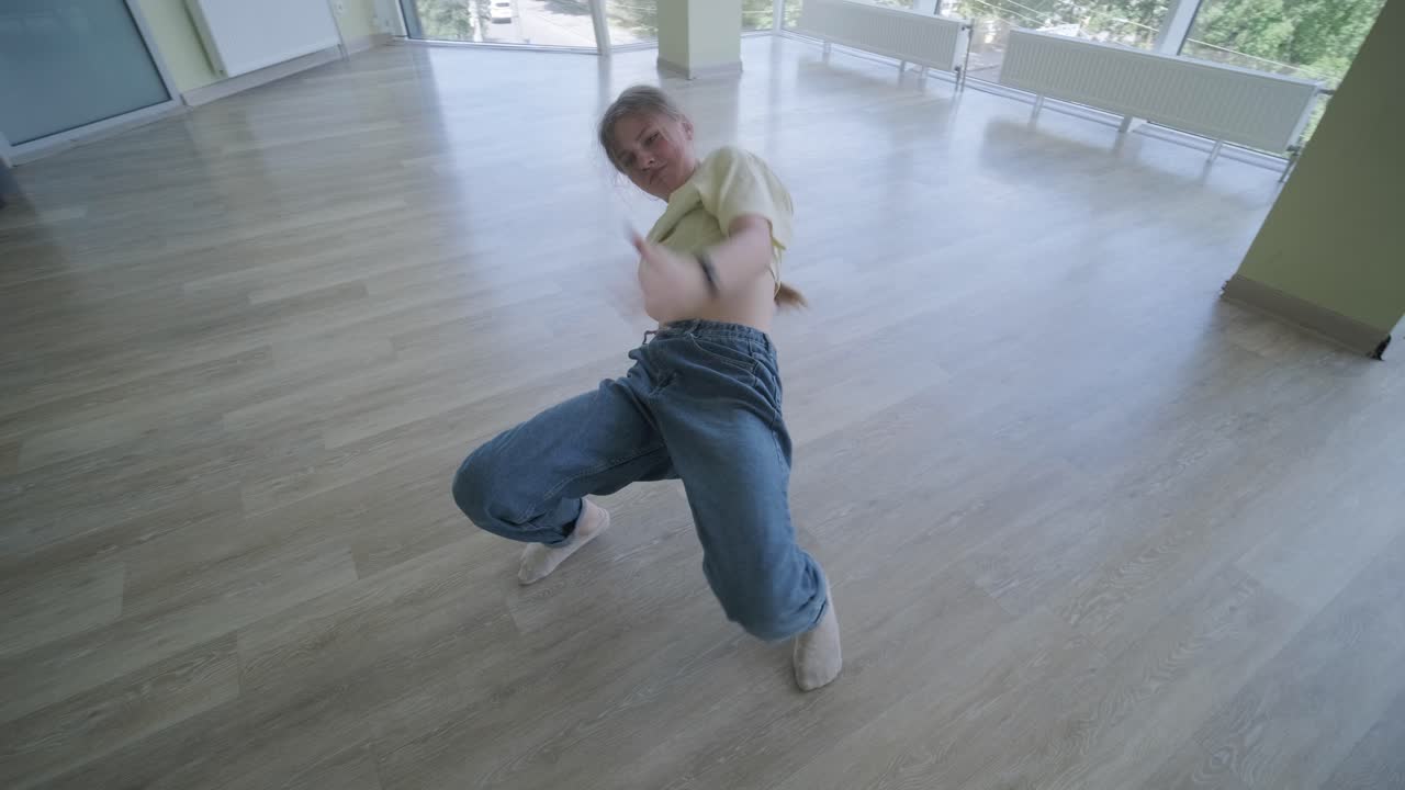 una chica joven bailando breakdance en un estudio moderno.