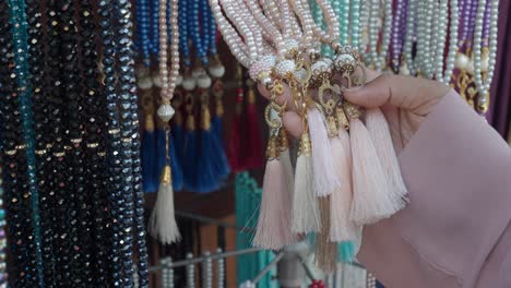 woman's hand choosing islamic prayer beads (tasbih) at a market