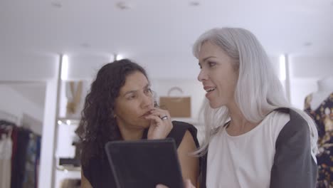 positive focused customer and shop assistant meeting with tablet computer