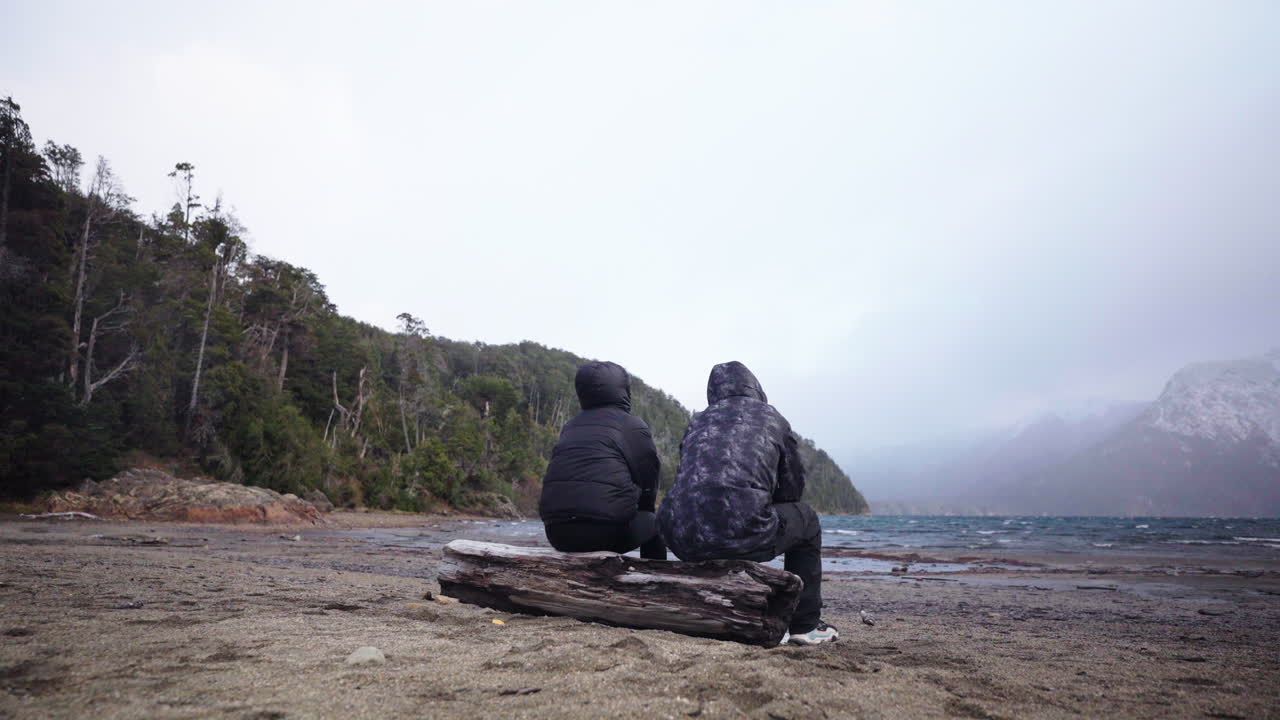 Gesture of support between traveling friends on patagonian lake, emotional connection, Argentina