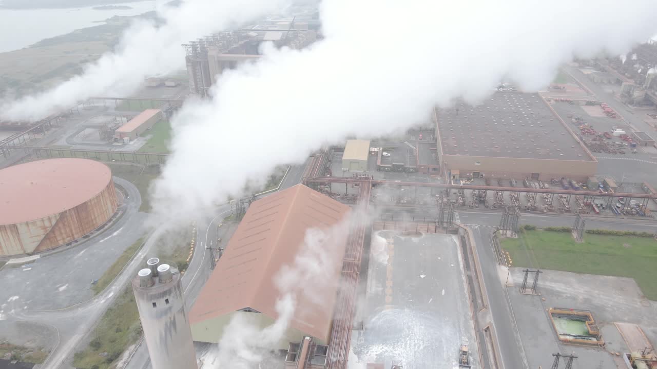 Aughinish alumina refinery in limerick, ireland with smoke rising from chimneys, aerial view