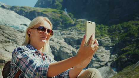 un turista feliz se hace selfie en el fondo de un glaciar en noruega viajando en concepto de noruega