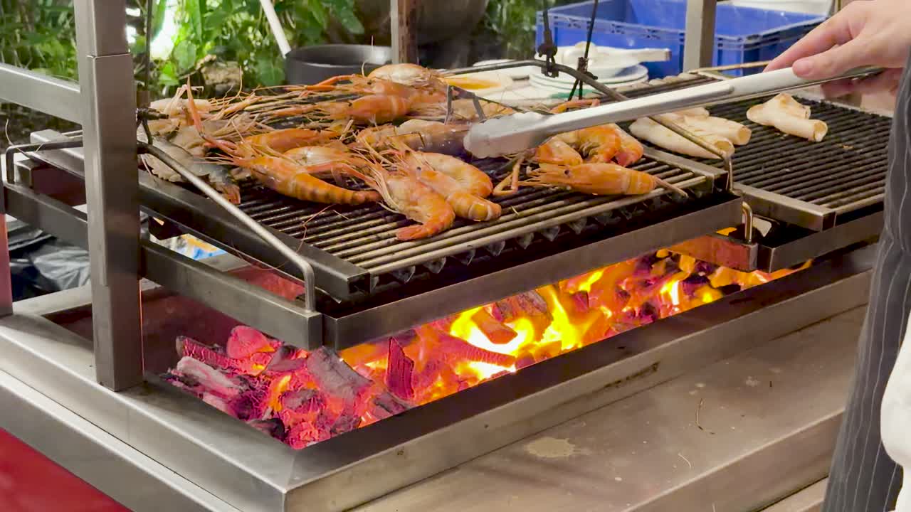 Chef grills river prawns and squid on charcoal barbecue, vibrant flames, outdoor Thai street food