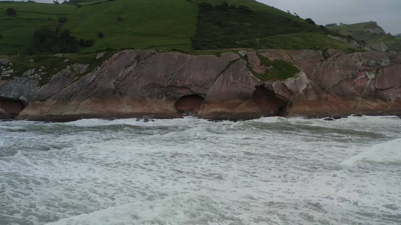 Grotte marine della spiaggia di Itzurun sulla costa di Zumaia, Spagna, mentre le onde si infrangono al rallentatore.